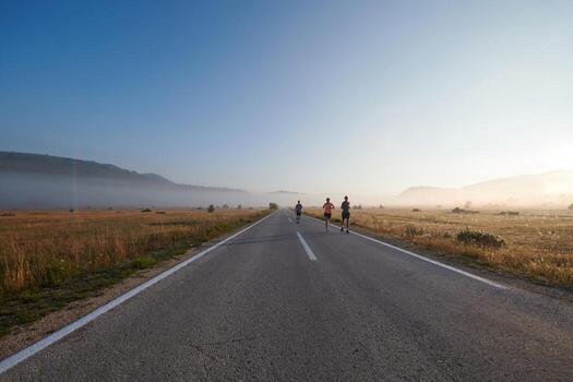 A group of friends, athletes, and joggers embrace the early morning hours as they run through the misty dawn, energized by the rising sun and surrounded by the tranquil beauty of nature photo