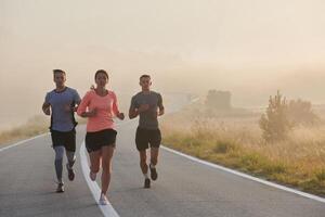 A group of friends, athletes, and joggers embrace the early morning hours as they run through the misty dawn, energized by the rising sun and surrounded by the tranquil beauty of nature photo