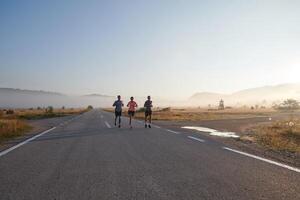 A group of friends, athletes, and joggers embrace the early morning hours as they run through the misty dawn, energized by the rising sun and surrounded by the tranquil beauty of nature photo