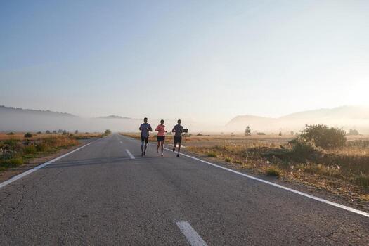 A group of friends, athletes, and joggers embrace the early morning hours as they run through the misty dawn, energized by the rising sun and surrounded by the tranquil beauty of nature photo