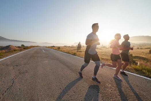 A group of friends, athletes, and joggers embrace the early morning hours as they run through the misty dawn, energized by the rising sun and surrounded by the tranquil beauty of nature photo