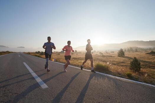 A group of friends, athletes, and joggers embrace the early morning hours as they run through the misty dawn, energized by the rising sun and surrounded by the tranquil beauty of nature photo