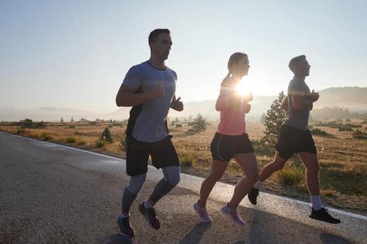 A group of friends, athletes, and joggers embrace the early morning hours as they run through the misty dawn, energized by the rising sun and surrounded by the tranquil beauty of nature photo