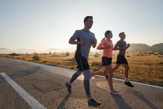 A group of friends, athletes, and joggers embrace the early morning hours as they run through the misty dawn, energized by the rising sun and surrounded by the tranquil beauty of nature photo