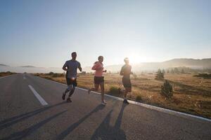 A group of friends, athletes, and joggers embrace the early morning hours as they run through the misty dawn, energized by the rising sun and surrounded by the tranquil beauty of nature photo