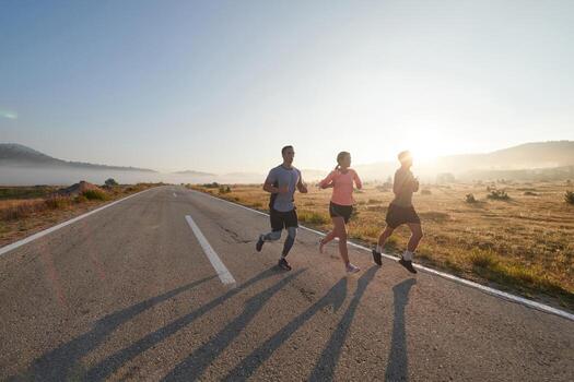 A group of friends, athletes, and joggers embrace the early morning hours as they run through the misty dawn, energized by the rising sun and surrounded by the tranquil beauty of nature photo
