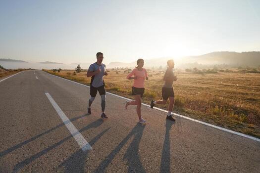 A group of friends, athletes, and joggers embrace the early morning hours as they run through the misty dawn, energized by the rising sun and surrounded by the tranquil beauty of nature photo