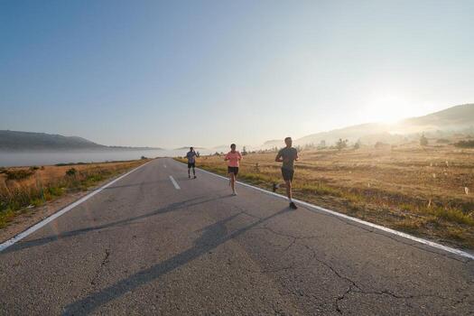 A group of friends, athletes, and joggers embrace the early morning hours as they run through the misty dawn, energized by the rising sun and surrounded by the tranquil beauty of nature photo