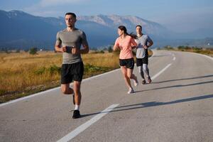 un grupo de amigos mantiene un sano estilo de vida por corriendo al aire libre en un soleado día, unión terminado aptitud y disfrutando el energizante efectos de ejercicio y naturaleza foto