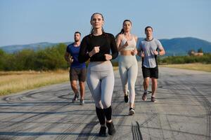 un grupo de amigos mantiene un sano estilo de vida por corriendo al aire libre en un soleado día, unión terminado aptitud y disfrutando el energizante efectos de ejercicio y naturaleza foto