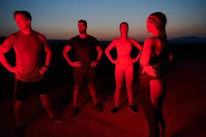 Diverse Athletes Unwind. Post-Marathon Rest Under Red Nighttime Glow. photo