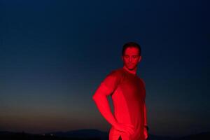 Athlete Strikes a Pose Under Red Nighttime Glow After Intense Daylong Marathon. photo