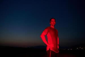 atleta huelgas un actitud debajo rojo Noche resplandor después intenso todo el día maratón. foto