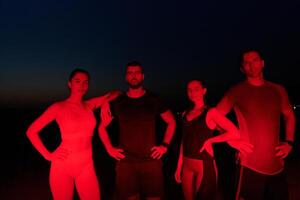 Diverse Athletes Unwind. Post-Marathon Rest Under Red Nighttime Glow. photo