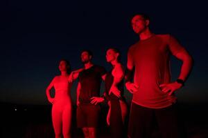 Diverse Athletes Unwind. Post-Marathon Rest Under Red Nighttime Glow. photo