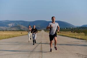 A group of friends maintains a healthy lifestyle by running outdoors on a sunny day, bonding over fitness and enjoying the energizing effects of exercise and nature photo