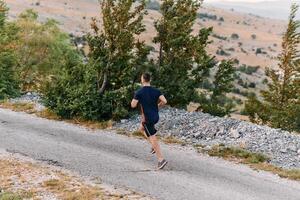 Determined Athlete Running Through Rugged Mountain Terrain at Sunrise. photo