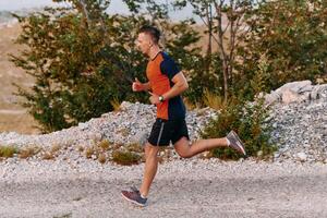 Determined Athlete Running Through Rugged Mountain Terrain at Sunrise. photo