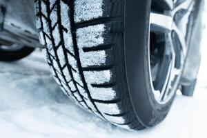 Car with winter tires on snowy road, closeup view photo