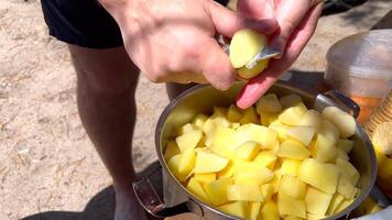 A close-up man cuts potatoes. Cooking barbeque in nature video