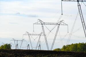 un Alto voltaje poder línea en el antecedentes de un rural campo. paisaje en el pueblo y eléctrico alambrado. foto