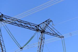 el construcción de un Alto voltaje poder línea en de cerca. alambres en un azul cielo antecedentes. foto