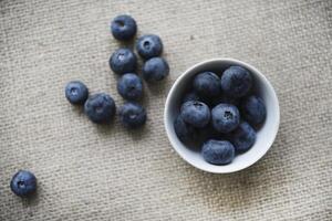 Blueberries in a white bowl on a burlap tablecloth. Juicy blueberries. photo