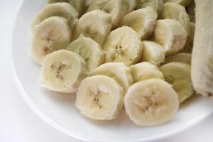 Sliced bananas on a white plate. Delicious and juicy fruits. Breakfast on a plate. photo