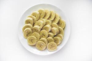 Sliced bananas on a white plate. Delicious and juicy fruits. Breakfast on a plate. photo