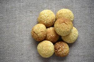 A pile of sesame cookies on a burlap bag. Sweet sugar yellow cookies. photo