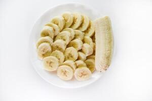 Sliced bananas on a white plate. Delicious and juicy fruits. Breakfast on a plate. photo