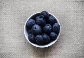 Blueberries in a white bowl on a burlap tablecloth. Juicy blueberries. photo