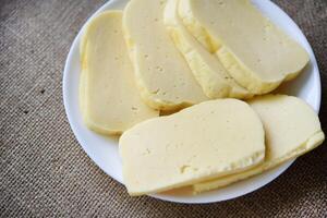 Slices of cheese cut on a plate. Delicious cheese with holes. photo