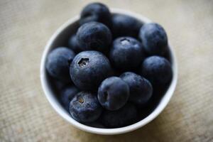 Blueberries in a white bowl on a burlap tablecloth. Juicy blueberries. photo