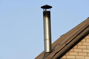 A chimney on a blue sky background. A shiny iron chimney. photo
