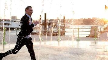 ung Lycklig affärsman dans glad i vatten fontän på solnedgång video
