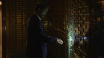 A man in a suit, looking professional, is seen accessing a banks secure deposit box video