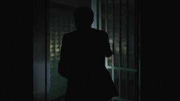un' misterioso figura nel un' buio camera con un' torcia elettrica, esplorando il sconosciuto con suspense video