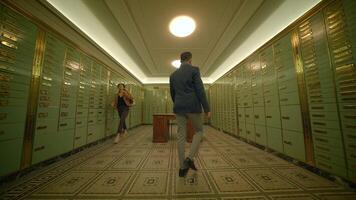 A man in a suit walking down a hallway lined with lockers in a brick building video