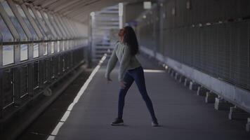 gelukkig jong vrouw met gekruld haar- dansen Aan stad straat in langzaam beweging video