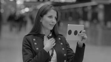 attraktiv und zuversichtlich jung Frau mit Handy, Mobiltelefon Tablette Bildschirm im das Stadt video