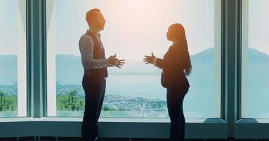 Two young business people talking together inside modern office lobby video