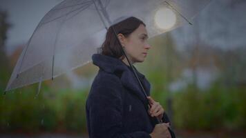 tveksam kvinna person innehav paraply i lynnig regnar väder video