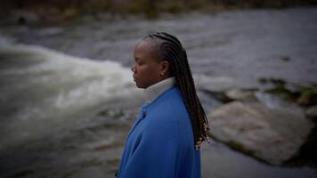 femelle la personne permanent dans lit de rivière à l'extérieur portant une bleu veste dans lent mouvement video