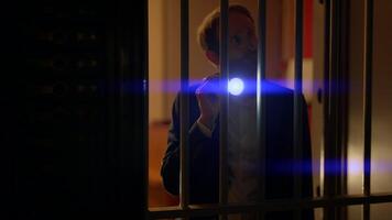 Man in suit spies Investigating vault safe holding a flashlight in dark room video