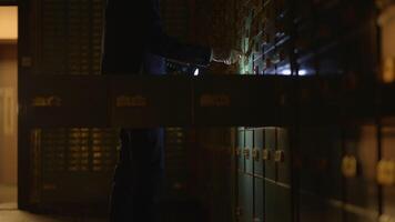 hombre en traje espías investigando bóveda seguro participación un Linterna en oscuro habitación video