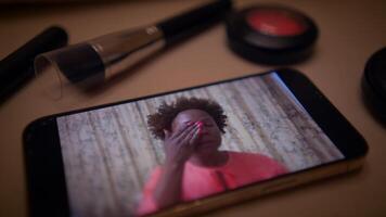 Woman follows a makeup tutorial on her smartphone to learn how to apply cosmetics online video