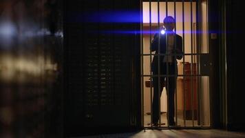 A security officer is examining a vault with a flashlight at a bank for safety inspection video