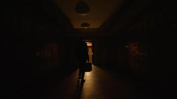 een silhouet door een Open deur in een vaag lit gang geeft een mysterieus en griezelig voelen video