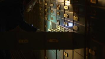 Person Accessing Safe Deposit Boxes in a Dimly Lit Secure Vault with a Flashlight video